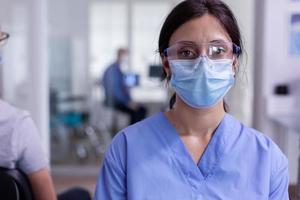 close-up van vermoeide verpleegster met beschermingsmasker tegen uitbraak camera kijken