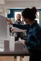 architectenarbeiders die blauwdrukken controleren met maquette foto