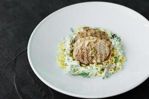 gerecht met stukjes vlees, pasta, greens, saus van een foie gras foto