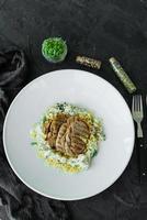 gerecht met stukjes vlees, pasta, greens, saus van een foie gras foto