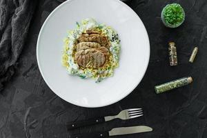 gerecht met stukjes vlees, pasta, greens, saus van een foie gras foto