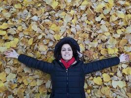 vrouw liggend op een tapijt van bladeren foto