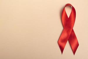 internationale aidsdag. rood lint op een beige achtergrond close up.banner. helpt bewustzijn concept. foto