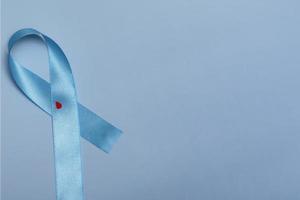 close-up bovenaanzicht van concept voor werelddiabetesdag 14 november. blauw lint met druppels bloed op een blauwe achtergrond