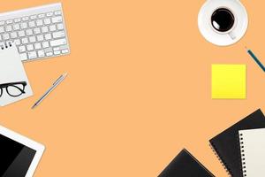 eenvoudige werkruimtetechnologie oranje tafel met laptop, koffiekopje, notitieboekje en kopieerruimte foto
