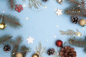 kerst plat leggen. concept foto kerst en nieuwjaar vakantie. dennenboom en gouden twijgen, kegels, sterren, slingers en sneeuwvlok op een blauwe achtergrond. kopieer ruimte voor tekst