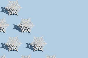 patroon van kerstboomversiering in de vorm van sneeuwvlokken op een blauwe achtergrond met kopieerruimte foto