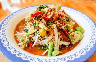 Papaya salade pittig met kousenband, kruiden en specerijen ingrediënten chili tomaat pinda knoflook geserveerd op tafel, thais eten bovenaanzicht. foto