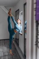 vrouw gymnast aan het doen moeilijk oefening voor balans en sterkte Aan opleiding in Sportschool foto