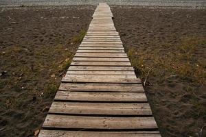 houten pad op het zandstrand. strandpromenade met de achtergrond van de zandtextuur foto