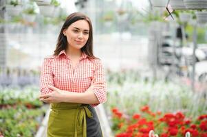 mooi vrouw tuinman nemen zorg van planten in haar bloemen en planten winkel - vrouw werken in een kas foto