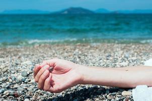 hand van een man ontspannen op het strand, turquoise zeewater op de achtergrond foto