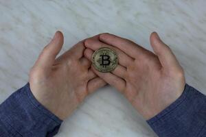 bitcoin in de handen van Mens, cryptogeld munt fysiek versie met een ingebouwd spaander met geld, duur munt voor investering foto