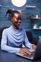 vrolijk Afrikaanse vrouw sprekend in de Cursus van telefoontje op zoek Bij laptop webcam in huis kantoor. zwart freelancer werken met van een afstand team chatten virtueel online conferentie. foto