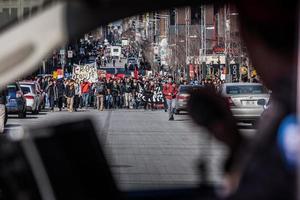 Montreal, Canada, 2 april 2015 - zicht op de eerste rij demonstranten die op straat door het raam van een politieauto lopen