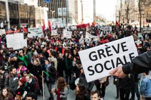 Montreal, Canada, 2 april 2015 - iemand die een zucht houdt en zegt greve sociale met een wazige demonstrant op de achtergrond. foto