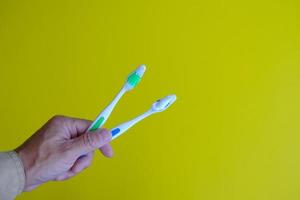 hand houdt een borstel tanden geïsoleerd op gele achtergrond en gezondheidszorg concept foto