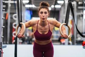 atletische vrouw die wat optrekoefeningen doet in de gymnastiekringen foto