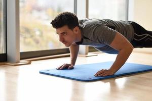 aantrekkelijke man die pushups doet in de sportschool foto