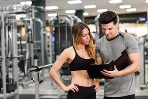 personal trainer en klant kijken naar haar vooruitgang in de sportschool foto