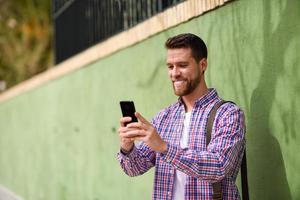 jonge man kijkt naar zijn smartphone op stedelijke achtergrond. levensstijl concept.