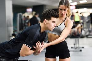 persoonlijke trainer die een jonge man helpt gewichten op te heffen foto