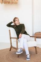 aantrekkelijke jonge vrouw zittend op de stoel in licht en luchtig interieur
