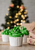kerstboomvormige cupcakes, omringd met feestelijke versieringen en lichtjes op de achtergrond foto