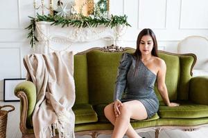 jonge vrouw zittend op de bank in een voor kerst ingerichte woonkamer foto