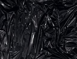 een transparante plastic folie op zwarte achtergrond. realistische plastic wrap-textuur voor overlay en effect. gerimpeld plastic patroon voor creatief en decoratief ontwerp.