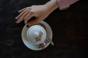 er staat een kop warme koffie op tafel. een meisje houdt een lekker drankje in haar hand. een soort genieten van vrije tijd. foto