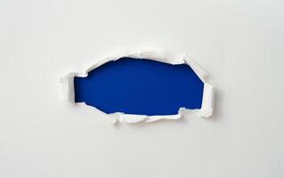 gescheurd papier frame met de gescheurde zijkanten. een blauw gat van gescheurd op het witte papier. realistisch gescheurd papier met de gescheurde randen voor kopieerruimte en tekst. foto