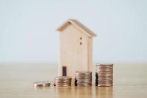 houten huis en stapelen van munten op houten tafel. geld besparen voor het kopen van een huis, financieel plan voor woningkrediet. foto