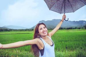 aziatische vrouwen reizen ontspannen in de vakantie. vrouwen staan in regenparaplu's. op de weide tijdens het regenseizoen.thailand foto