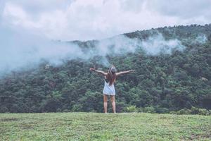 aziatische vrouwen reizen ontspannen in de vakantie. staande handen op wild natuurhout op de berg. foto