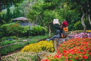 vrouw reizen natuur in de bloementuin. ontspan zittend op rotsen en lees boeken midden in de natuur in het nationale park doi inthanon. foto