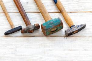 set van oude ijzeren hamers op een witte houten tafel. foto