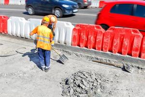 wegwerkers slopen oud beton tijdens wegreparaties en scheppen een werkterrein op. foto