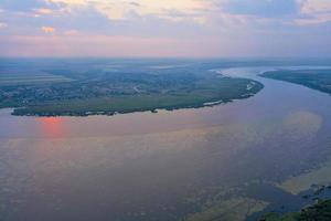 mistige zonsopgang boven een brede rivier op een zomerdag, landschap vanuit vogelperspectief. foto