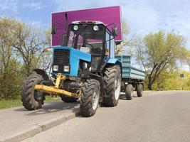 oude kleine blauwe tractor met een kar staat aan de rand van het park foto