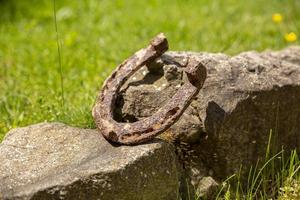 close-up van een oude roestige hoefijzer gestut op een grote steen. foto