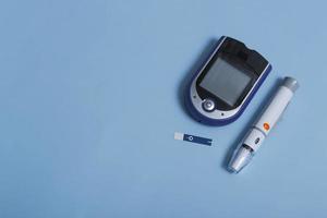 bloedglucosemeter, teststrips en spuit voor het bewaken van diabetes mellitus met kopieerruimte geïsoleerd op een gekleurde achtergrond. foto