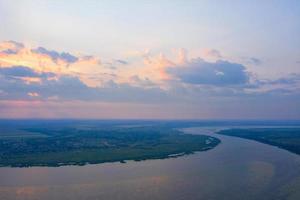 mooie lucht bij mistige zonsopgang boven een brede rivier op een zomerdag, landschap vanuit vogelperspectief. foto