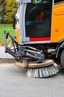 de roterende voorveegwagen autoborstels verwijderen gevallen bladeren van de weg. foto