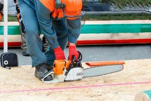 een man start een kettingzaag op een werkterrein voor een houthakkerswedstrijd. foto