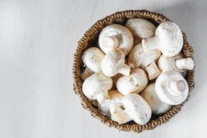 champignons champignons in een ronde rieten mand op een witte houten tafel foto