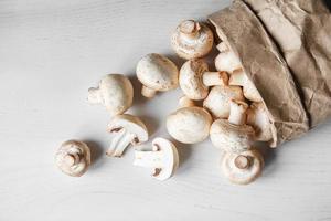 champignons champignons in papieren zak op een witte houten tafel