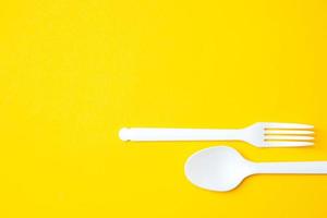 plastic witte lepel en vork op gele achtergrond