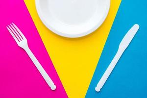 plastic witte vork, mes en plaat op veelkleurige achtergrond foto