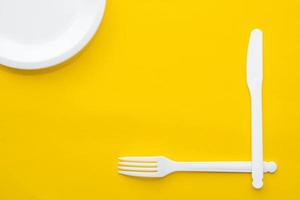 plastic witte vork, mes en plaat op gele achtergrond